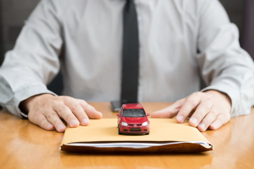 Man with a manila folder full of paperwork, with a red toy car