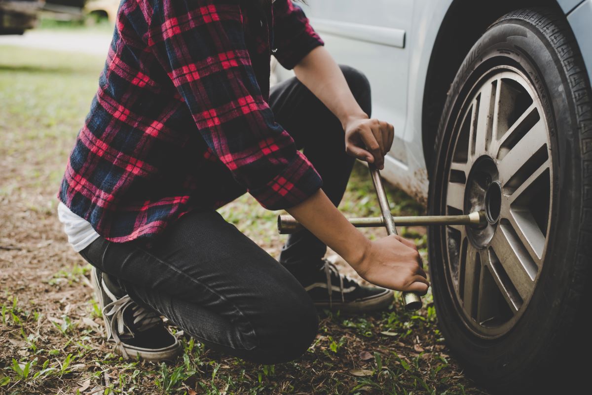 person using a tire iron on a flat tire